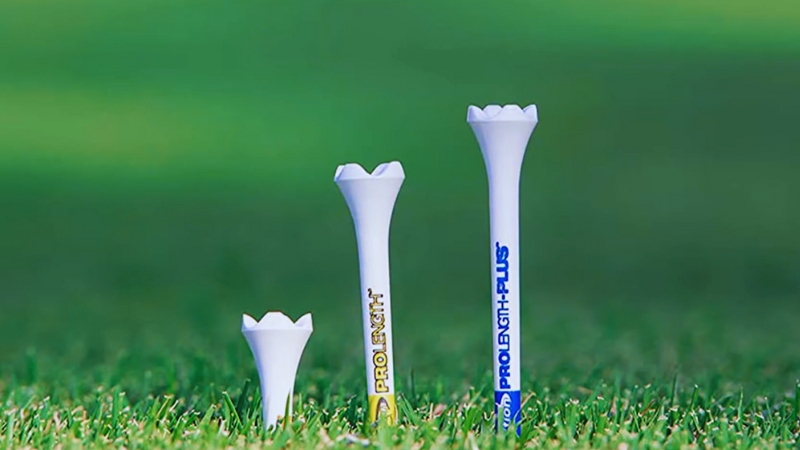 Three Golf Tees of Different Heights Are Lined up On Grass